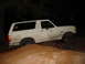 1989 Ford Bronco - White 1989 Ford Bronco navigates an off-road trail in the dark.