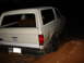 1989 Ford Bronco - This white SUV is stuck in a muddy ditch at night. A 'Blue Ridge 4x4' sticker is visible on the rear.