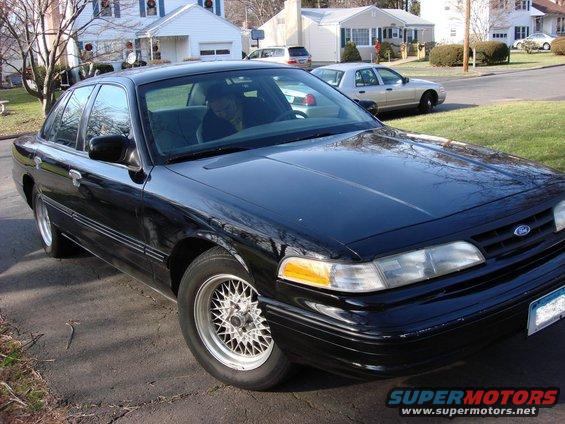 Black Ford Crown Victoria parked in a driveway, another car in background