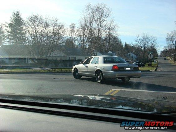 2003 Ford Crown Victoria sedan driving away from camera on a suburban street