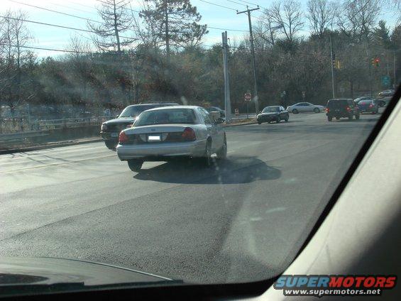 Silver 2003 Ford Crown Victoria driving on a road, seen from behind