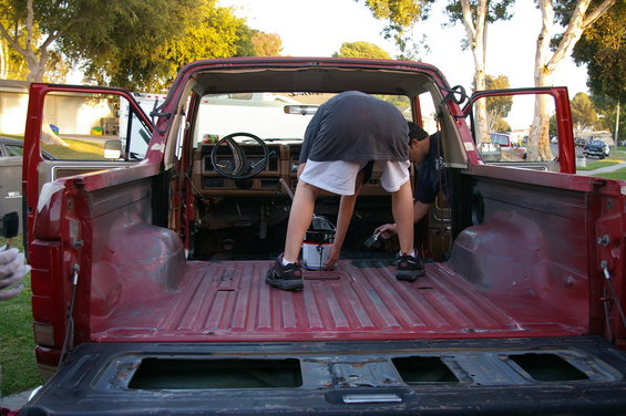guy painting inside red pickup truck bed