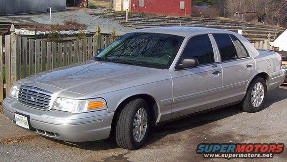Silver sedan parked outside a building with a wooden fence behind it