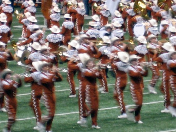 Marching band in orange and white uniforms on a green field