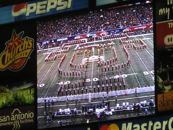 Marching band on football field spelling out '2006 ALAMO BOWL' with Pepsi and Church's Chicken logos visible