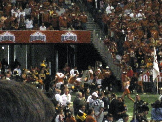 Crowd at a football game with 'ALAMOBOWL' banner visible
