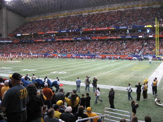 Crowded football stadium with orange-clad spectators and a marching band on the field