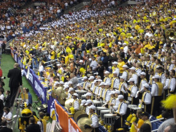 Crowd in stadium with marching band playing drums and cymbals