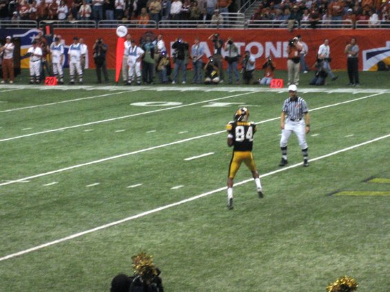 football player with number 84 on field during game, referee nearby