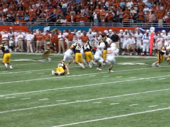 football players in action on a field during a game, with spectators in the background