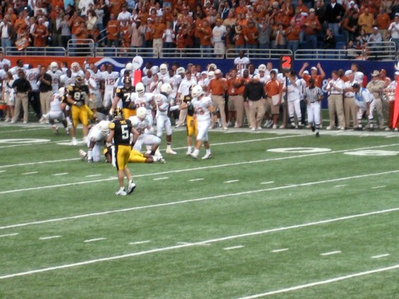 Football players on a field during a game, with spectators in the background