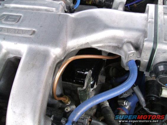 Engine intake manifold with V6-VALVE marking, copper and blue hoses, and SuperMotors.net logo