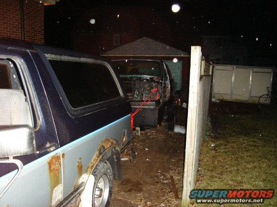 Two SUVs in a yard at night, one with its engine compartment open