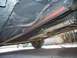 1992 Ford Taurus - The undercarriage of a vehicle is visible, including the exhaust pipe and a portion of the rear tire.