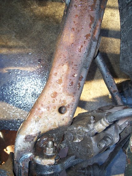 Close-up of a rusty suspension part covered in water droplets