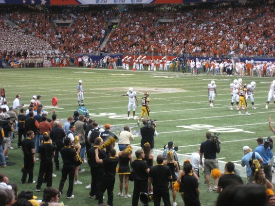 Football players on a field with a large crowd in the stands