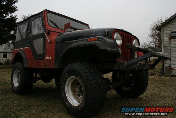 Red and black Jeep CJ5 with soft top, lifted suspension, and aftermarket bumper