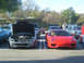 1985 Ford Mustang - A red Ferrari sports car is parked at a car show, with its hood open, alongside other vehicles.