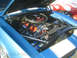 1985 Ford Mustang - The engine bay of a blue 1969 Chevrolet Camaro is open, revealing its V8 engine and chrome details.