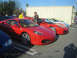 1985 Ford Mustang - Several red Ferraris are parked in a row at an outdoor car show.