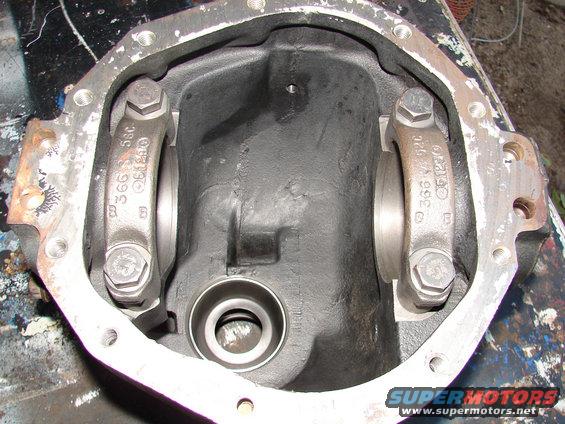 Differential housing with bearing caps and bolts. Part numbers visible on caps