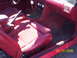1990 Ford Mustang - The interior of a 1990 Ford Mustang features red ribbed seats and a matching dashboard.