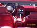 1990 Ford Mustang - The interior of a red convertible shows the dashboard, seats, and center console, with a date stamp in the corner.
