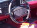1990 Ford Mustang - The interior of a 1990 Ford Mustang shows red carpeting and seats, a black steering wheel, and dashboard instrumentation.