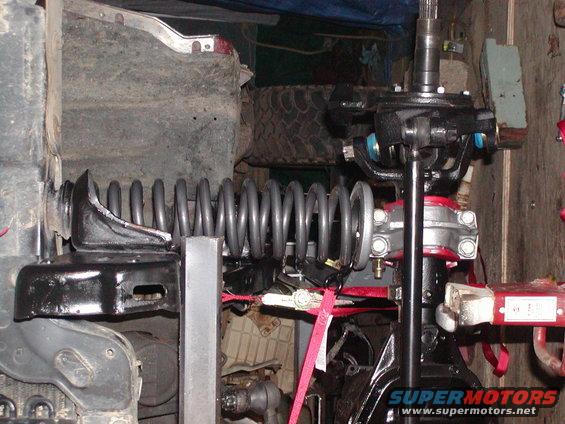 Close-up of a vehicle's front suspension with a large coil spring and steering components