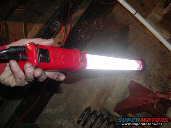 hand holding a red circuit tester with a bright light