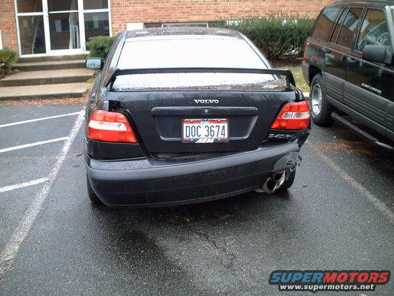 Rear of a black Volvo S40 with significant damage to the right rear bumper and taillight. Another SUV is parked to its right