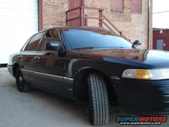Black 1992 Ford Crown Victoria sedan, front 3/4 view, parked outside a brick building