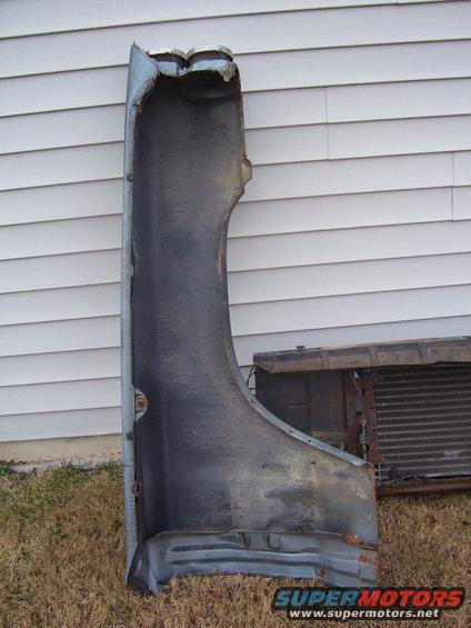 car fender and radiator sitting on grass in front of a house