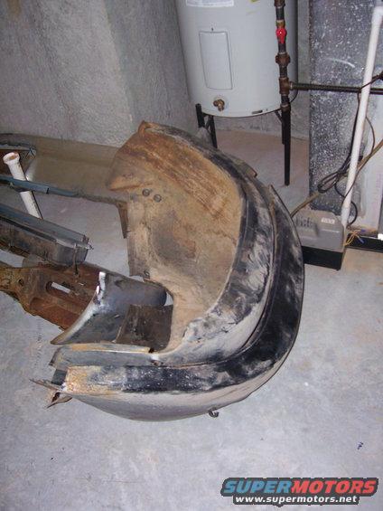 Damaged car bumper, possibly from a 1960s model, lying on a concrete floor next to a water heater