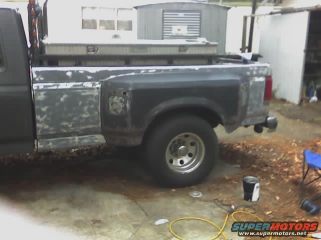 1990 Ford F-350 dually truck bed, showing primer and some rust. A toolbox is mounted on the bed