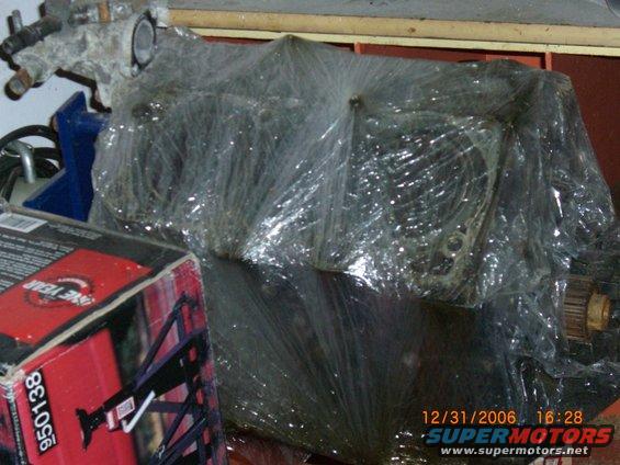 Engine block wrapped in plastic with a box labeled 'ONE YEAR' in the foreground