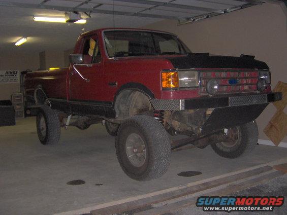 Red 1990 Ford F-150 pickup truck with lifted suspension and aftermarket bumper