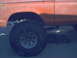 1978 Ford Bronco - The orange paint on this vehicle is dirty and shows some wear. The tire is large and appears to be for off-road use.