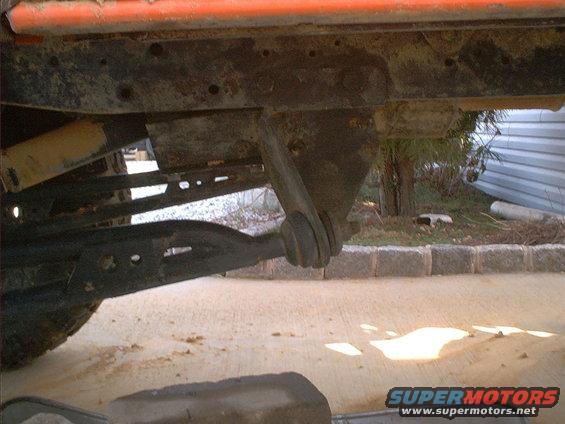 Orange vehicle frame with suspension components and a tire visible