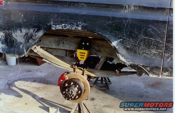 Rear leaf spring suspension with red brake caliper and yellow shock absorber mount