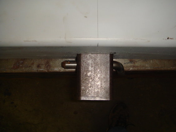 Rear bumper latch mechanism with pin and curved pipe
