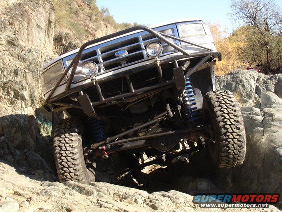 White off-road vehicle with custom roll cage climbing rocky terrain