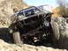 1984 Ford Bronco - This modified off-road vehicle navigates a challenging rocky incline, its robust suspension and aggressive tires.