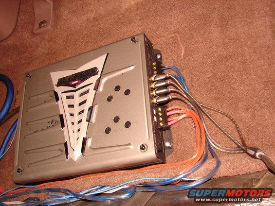 car amplifier with wires connected, sitting on carpeted surface