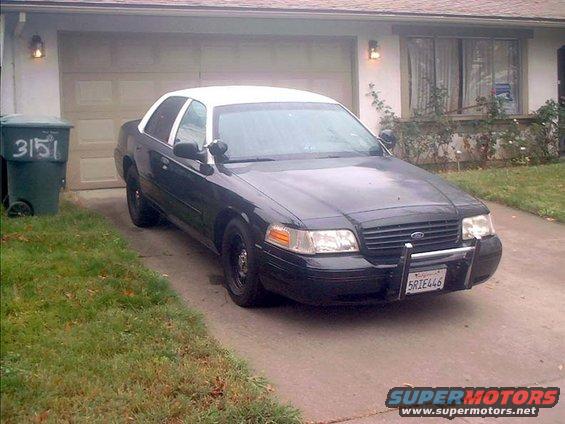 Black and white Ford Crown Victoria parked in driveway. License plate 5RIE446