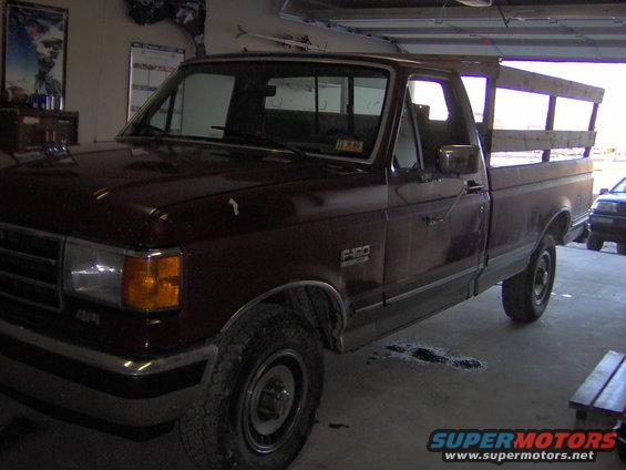 Maroon 1991 Ford F-150 pickup truck with wooden bed rails, parked indoors