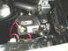 1966 Ford Fairlane - Close-up view of a car battery and radiator hose within the engine compartment.
