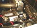 1966 Ford Fairlane - Close-up view of a car battery and radiator hose under the hood of a vehicle.
