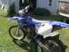 1977 Ford F-250 - A blue dirt bike is parked on grass in front of a house and deck.