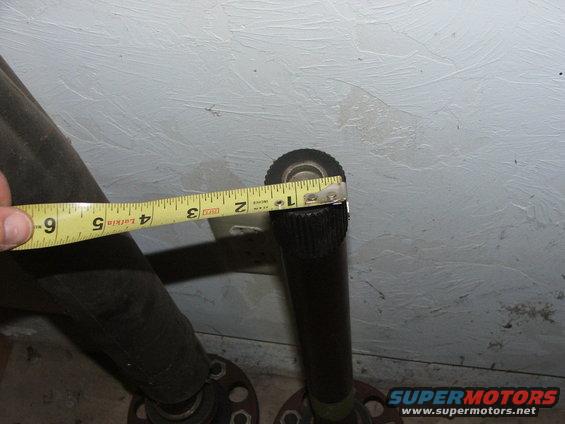 Axle shafts being measured with a yellow tape measure against a textured wall